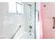 Updated shower features white tiles, grab bars, glass door, and bright window at 1403 5Th Pl, Las Vegas, NV 89104