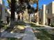 A sidewalk in a housing community is lined with trees, green grass and two-story condos at 2679 Jacyra Ave, Las Vegas, NV 89121