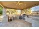 Covered outdoor kitchen features tile flooring, bar seating, ceiling fan and built in grill at 308 Bayswater Ct, Las Vegas, NV 89145