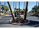 View of the community's entrance featuring mature palm trees, water feature, guardhouse, and circular landscaping at 3126 Asoleado Cir, Las Vegas, NV 89121