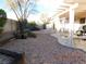 Spacious backyard with a covered patio, desert landscaping, and mature trees, perfect for relaxing or entertaining at 3951 Candleglow Ct, Las Vegas, NV 89147