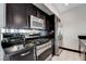 Close-up view of a kitchen with stainless steel gas range, granite counter, and dark wood cabinets at 4565 Dean Martin Dr # 102, Las Vegas, NV 89103