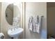 Small bathroom with pedestal sink, oval mirror, and beige walls at 528 Copper View St, Henderson, NV 89052