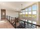 Hallway with wood floors and contemporary railings overlooking the living area with large windows at 5436 Succulent Rose Dr, Las Vegas, NV 89135