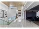 Bright hallway featuring a sleek glass railing, modern artwork, and recessed lighting, leading to a spacious living area at 631 Cityview Ridge Dr, Henderson, NV 89012