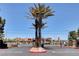 Gated community entrance with mature palm trees and commercial businesses in the background under a clear blue sky at 7885 W Flamingo Rd # 1037, Las Vegas, NV 89147