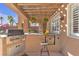 Outdoor kitchen with grill and bar seating under a wooden pergola at 8501 Vivid Violet Ave, Las Vegas, NV 89143