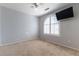 This is a spacious bedroom with a ceiling fan, carpet, and a large window with plantation shutters at 9843 Frosty Canyon Ct, Las Vegas, NV 89183