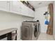 Modern laundry room with front load washer/dryer and overhead cabinets at 9916 Sierra Canyon Way, Las Vegas, NV 89147