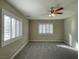 Spacious carpeted bedroom with a ceiling fan and two windows at 12048 La Palmera Ave, Las Vegas, NV 89138