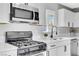 Close-up of the kitchen features stainless steel appliances, quartz countertops, modern faucet and white cabinets at 139 Ivy St, Henderson, NV 89015