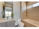 Bathroom showcasing a tub with beige tile and a vanity with a mirrored wall at 1469 Dragon Stone Pl, Henderson, NV 89012