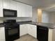 Modern kitchen with white cabinets, black appliances, gray countertops and vinyl plank flooring at 2420 Sweetgum St, Las Vegas, NV 89108