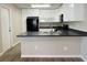 Clean kitchen featuring white cabinets, black appliances, gray countertops and vinyl plank flooring at 2420 Sweetgum St, Las Vegas, NV 89108