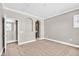 A bedroom featuring neutral walls, carpet flooring, and an arched alcove leading to an adjacent bathroom at 25 Via Mantova # 2, Henderson, NV 89011