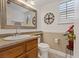 Small bathroom with wood vanity, white toilet, and decorative mirror at 3321 Mariner Bay St, Las Vegas, NV 89117