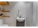 A compact bathroom featuring floating wood shelves and white-and-gray wavy shower tile and curtain at 3327 Rio Grande St, Las Vegas, NV 89115