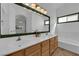 Bathroom features double sinks, wood cabinets, a large framed mirror, and a bathtub at 3923 Gramercy Ave, North Las Vegas, NV 89031