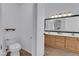 Bathroom with a toilet, wood cabinets, double sinks, a framed mirror, and tile floors at 3923 Gramercy Ave, North Las Vegas, NV 89031