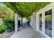 Covered patio with seating area, lush greenery, and access to the backyard at 5880 W Oquendo Rd, Las Vegas, NV 89118