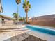 Backyard with a private pool, stone patio, palm trees, and a white metal fence at 8474 Orange Cliff Ct, Las Vegas, NV 89123