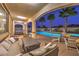 Inviting covered patio area with comfortable seating, ping pong table, and views of the sparkling pool and swaying palm trees at twilight at 12259 Pacific Cruise Ave, Las Vegas, NV 89138