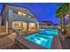 Night shot of the home's exterior showing a well-lit pool, spa, and patio area perfect for evening relaxation and entertainment at 12259 Pacific Cruise Ave, Las Vegas, NV 89138