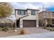 Beige two-story home featuring a brown two-car garage, a brick driveway and desert landscaping at 2240 Sky Island Dr, Henderson, NV 89002