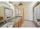 Bright bathroom featuring dual sinks with granite countertops and a walk-in shower with glass door at 5625 W Agate Ave, Las Vegas, NV 89139