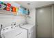 Bright laundry room with white washer and dryer, storage, and a gray door at 714 Arrowhead Trl, Henderson, NV 89002