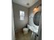 Powder room with tiled floor features a pedestal sink, a round mirror, and natural light from the window at 7732 Hand Woven Ct, Las Vegas, NV 89149