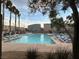 Community pool area with lounge chairs surrounded by palm trees, offering a resort-style living experience at 7732 Hand Woven Ct, Las Vegas, NV 89149