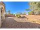 A partially-covered backyard featuring decorative rock, a brick perimeter, mature landscaping and tall brick walls at 1056 Flatfoot Ave, Henderson, NV 89012