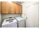 Spacious laundry room has wooden cabinetry for storage, front loading washing machine, and dryer at 1056 Flatfoot Ave, Henderson, NV 89012