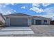 Charming single-story home featuring a two-car garage, tiled roof, and neutral color palette against a cloudy sky at 121 Comstock St, Pahrump, NV 89048