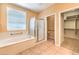 Bright primary bathroom featuring a bathtub, glass-enclosed shower, and a doorway to the walk-in closet at 2277 Canyonville Dr, Henderson, NV 89044