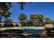 Community pool surrounded by mature trees and lush green lawns, offering a relaxing retreat at 271 Greenbriar Townhouse Way, Las Vegas, NV 89121