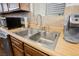 Bright kitchen features stainless steel sink, appliances, wood cabinetry, tile backsplash and double basin sink at 271 Greenbriar Townhouse Way, Las Vegas, NV 89121