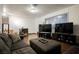 Open living room with wood floors, gray sofa, large window, and three large televisions at 271 Greenbriar Townhouse Way, Las Vegas, NV 89121