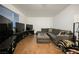 Spacious living room with wood floors, gray sofa, large window, and multiple televisions at 271 Greenbriar Townhouse Way, Las Vegas, NV 89121