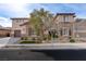 Two-story house with stone and stucco exterior, brown garage doors, and landscaped yard at 37 Carolina Cherry Dr, Las Vegas, NV 89141