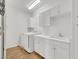 Well-lit laundry room with white cabinets, utility sink, washer, dryer, and hardwood floors at 2050 W Warm Springs Rd # 3322, Henderson, NV 89014