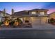 Elegant two-story home with a tile roof, a three-car garage, well-maintained landscaping, and inviting curb appeal at twilight at 4439 Melrose Abbey Pl, Las Vegas, NV 89141