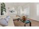 Comfortable living room featuring a modern white sofa, stylish glass coffee table, and plantation shutters at 4439 Melrose Abbey Pl, Las Vegas, NV 89141