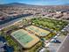 Aerial view of community tennis courts, landscaping, parking, and surrounding neighborhood homes against a mountain backdrop at 723 Orange Plume Walk # 0, Henderson, NV 89011