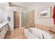 Bright bathroom featuring a soaking tub, glass shower, and neutral tile flooring at 830 Cozette Ct # 102, Las Vegas, NV 89144