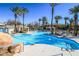 Resort-style community pool surrounded by swaying palm trees and comfortable lounge chairs on a sunny day at 830 Cozette Ct # 102, Las Vegas, NV 89144