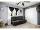 Bedroom with a gray wall and a black futon couch with a ceiling fan above a carpeted floor at 8651 Moreno Mountain Ave, Las Vegas, NV 89178
