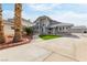 Home featuring a spacious concrete driveway with desert landscaping, palm trees, and a private gated entrance at 2327 River City Dr, Laughlin, NV 89029