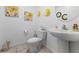 Powder room featuring a pedestal sink, toilet and yellow floral wall decor at 3558 Herodain Ave, Las Vegas, NV 89106